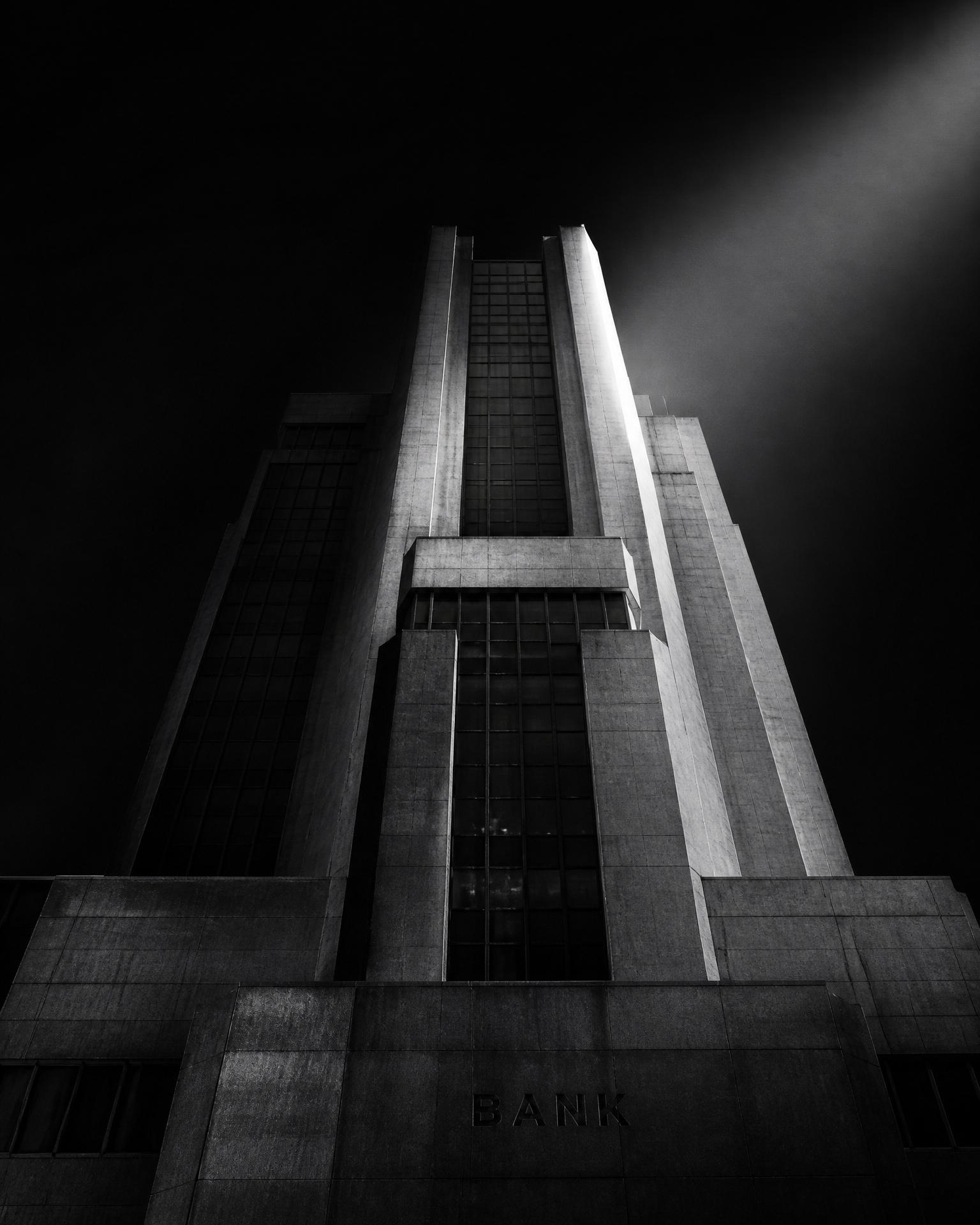 Institutional bank tower rising against a dark sky